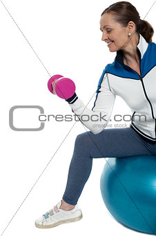 Woman on swiss ball working out with dumbbells