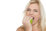 Sexy blonde female eating fresh green apple