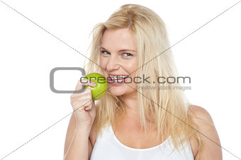 Health conscious woman about to take bite from green apple
