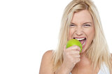 Closeup shot of a blonde woman biting an apple