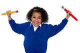 Fun loving elementary girl dancing with pencils in both her hands