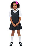 Cheerful young kid in pinafore dress posing smilingly