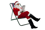 Kris Kringle relaxing and using electronic tablet