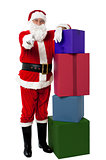 Smiling senior Santa posing beside colorful stack of Xmas presents