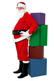 Santa leaning over colorful pile of Xmas presents