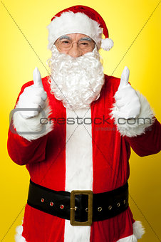 Cheerful male in Santa costume showing double thumbs up