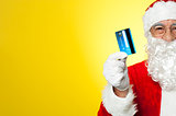 Cropped image of aged Santa holding credit card