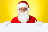 Male Santa standing behind big blank banner ad board