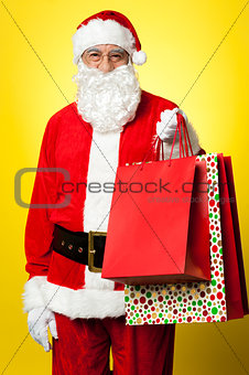Joyous Santa posing with colorful shopping bags