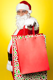 Cheerful Santa holding vibrant colored shopping bags
