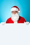 Aged Santa standing behind a blank ad board