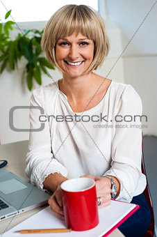 Casual woman in office enjoying her coffee break