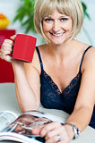 Pretty woman with a coffee mug in hand reading magazine
