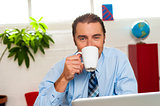 Smiling male manager enjoying hot coffee