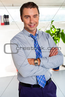 Young manager in formals standing with arms crossed