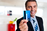 Cheerful businessman holding up his credit card