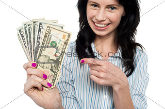 Happy woman holdng and pointing towards dollar notes