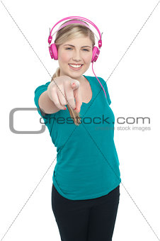 Young girl enjoying music and pointing at you