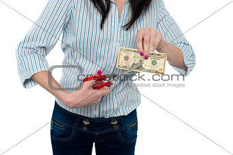 Woman cutting ten dollar banknote with scissors