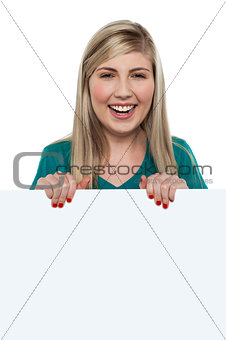 Smiling teen girl standing behind blank whiteboard