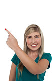 Blonde girl pointing away on white background