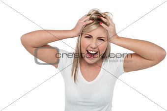 Young girl screaming loud while holding her head