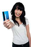 Joyous brunette showing her credit card to you