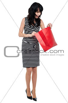 Young woman searching for her gift inside bag