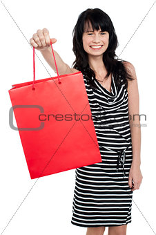 Smiling woman offering bag full of gifts