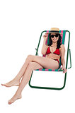 Stylish female bikini model relaxing in canvas chair