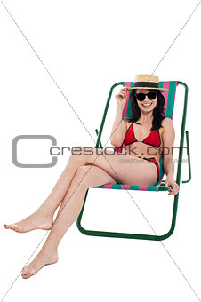 Stylish female bikini model relaxing in canvas chair