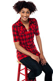 Curly haired fashion model sitting on red stool
