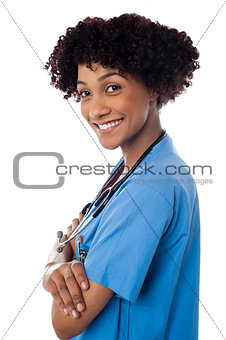 Smiling female physician standing sideways with folded arms