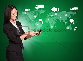 Smiling businesswoman in suit standing and using mobile phone 