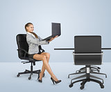 Businesslady sitting half-turned in chair and looking at laptop