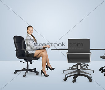 Businesslady sitting half-turned at table with folder in her hands