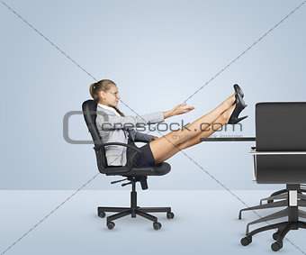 Businesslady sitting profile in chair with her crossed legs on table