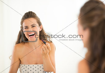 Portrait of smiling young woman with lipstick in bathroom