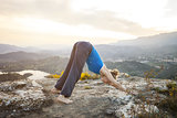 Young Caucasian woman performing downward dog yoga pose outdoors