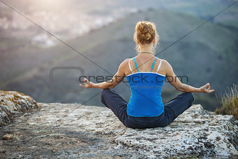 Young woman sitting in asana position and enjoying valley view