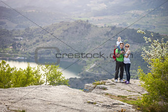Young couple with toddler boy standing on cliff and smiling