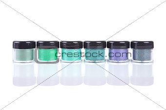 Row of green mineral eye shadows in clear plastic jars 