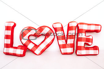Funny love word of plush red letters on white background. Full plaid textile