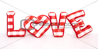Funny love word of plush red letters on white background. Full plaid textile