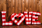 Love word of plush red letters on wood background. Full plaid textile