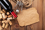 Red wine bottle, corks and corkscrew over wooden table backgroun