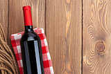 Red wine bottle over towel on wooden table