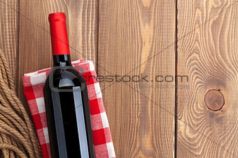 Red wine bottle over towel on wooden table