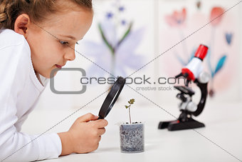 Young girl study a plant growing in plastic recipient