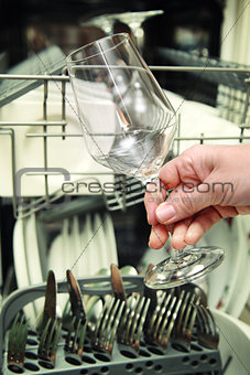 Kitchen Woman with a clean wine glass on background dishwasher